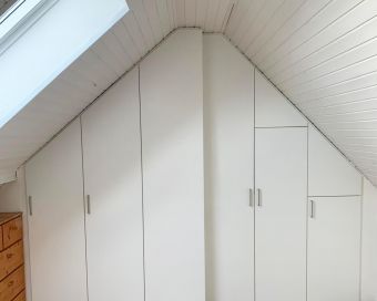Passgenaue Einbauschränke in Weiß unter einer Dachschräge – maßgefertigte Stauraumlösung für Köln und Leverkusen